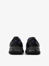 Mocasín New Balance modelo U1906LAR, color negro con detalles en gris y azul. Presenta una capellada de cuero con relieve de cocodrilo y una correa de velcro en el empeine. Cuenta con suela acolchada 860v2 con tecnología ABZORB SBS en el talón.