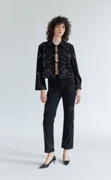 Pantalón de denim blanco con tachas plateadas.