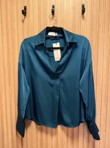 Blusa de seda color fucsia, de corte holgado y mangas largas con puños abotonados.