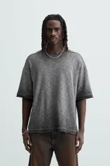 Camiseta gris de punto con efecto lavado, corte holgado, cuello redondo y mangas cortas.