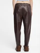 Pantalón negro de cuero sintético con corte slim fit, cintura elástica con cordón ajustable y bolsillos laterales. Acabado vintage.