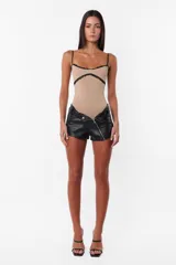 Short negro de cuerina con cierre diagonal desmontable, tiro medio y broches snap en el delantero.
