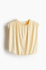 Top cropped color crema, sin mangas, de punto suave con costuras fruncidas para una silueta abullonada con efecto drapeado.