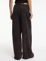 Pantalón negro de tiro alto y pierna recta, con pretina elástica y lazos ajustables.