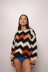 Buzo tejido a mano con lana merino, estilo oversized con diseño de ondas en colores beige, negro, naranja y marrón.