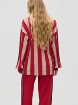 Cardigan rojo y beige a rayas verticales, de corte holgado y caída suelta. Tiene botones metalizados, logo bordado en el frente y puños acanalados.