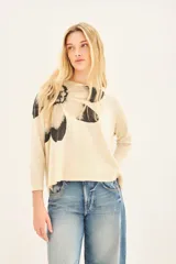 Sweater color crema con estampado de flor en tonos grises y negros en el frente.