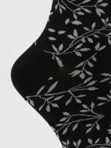 Calcetín de caña media color negro con diseño tejido de ramas y hojas en color gris claro. El borde superior tiene un acabado festoneado.