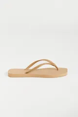 Ojotas color beige con base texturizada y tiras con diseño trenzado y logo de la marca.