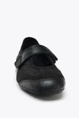 Zapato tipo bailarina color negro, con capellada de rejilla y cierre con tira de velcro.