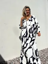 Vestido largo blanco con estampado abstracto en negro, escote en V y mangas largas.