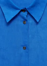 Camisa blanca de lino con cuello clásico, manga corta y cierre frontal con botones.