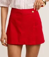 Short pollera de cintura alta confeccionado en sarga color rojo, con traspase sobre y botón diferenciado.