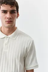 Remera polo blanca de punto texturizado de peso medio. Modelo de manga corta con cuello, tapeta de botones y bajo recto. Corte ajustado que realza el contorno del cuerpo creando una silueta entallada.