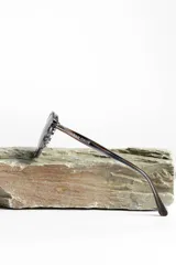 Lentes de sol unisex con montura redonda negra y lentes degradadas de gris a transparente.