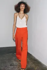 Pantalón de tiro alto color naranja, corte wide leg y largo hasta el tobillo. Tiene bolsillos de parche delanteros y cierre frontal con cremallera y botón.