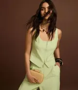 Chaleco corset de sastrería color verde claro, con escote en U, cierre frontal con cremallera, bolsillos falsos y bajo en V.