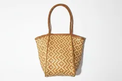 Bolso tote de cuero trenzado en tonos marrón y negro, con asas de cuero trenzado color bordó.