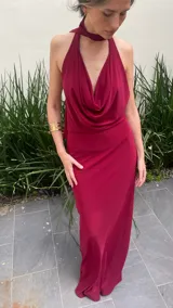 Vestido largo color borgoña, con escote drapeado y cuello halter. Tiene forro corto con transparencia.