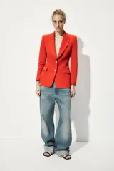 Blazer color rojo con cuello solapa, manga larga con hombreras, bolsillos delanteros con solapa y cierre frontal con botones dorados.