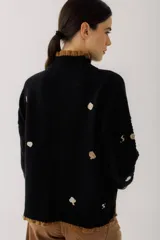 Sweater crudo de tejido de punto con cuello alto con volados y bordados de símbolos de naipes.