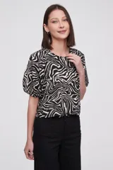Blusa con estampado animal print en blanco y negro, de mangas cortas abullonadas y cuello redondo.