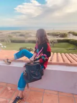 Sweater negro con detalles bordados de colores en el frente y mangas largas. Tiene cuello redondo y puños y ruedo acanalados. El cuerpo es de color rojo y las mangas son negras.