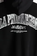 Campera negra con capucha, cierre frontal y bolsillos laterales. Estampado blanco con texto en el pecho.