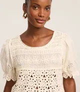 Blusa color crudo de ganchillo con mangas cortas abullonadas y bordados de flores.