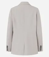 Blazer largo color beige, de corte recto, con cuello solapa, cierre frontal con doble botón, bolsillos tipo ojal y mangas largas con botones decorativos en los puños.