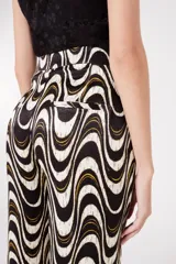 Pantalón palazzo con estampado de ondas en tonos blanco, negro y dorado.