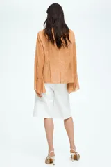 Blusa de gasa color ocre con estampado de piel de serpiente, escote en V pronunciado con tiras diagonales y mangas extralargas acampanadas.