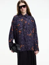 Camisa de viscosa estampada con flores color naranja sobre fondo azul marino. Tiene botones en la parte delantera y lazo ajustable.