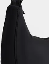Cartera saca negra de tela deportiva con correa regulable, cierre superior y bolsillo frontal con cierre. Incluye charm lateral.
