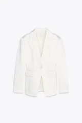 Blazer blanca de tejido satinado, con cuello solapa y escote pico, manga larga con hombreras, bolsillos con solapa en delantero y falso bolsillo en pecho, bajo con abertura en espalda y cierre frontal con botón.