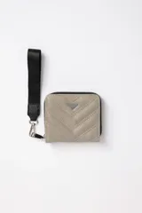 Billetera cuadrada color gris topo, con diseño capitoneado en diagonal, cierre perimetral con cremallera negra, tira de agarre de mano y logo triangular metálico.