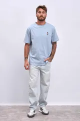 Remera celeste de corte recto y manga corta, con pequeño estampado de una lata en el pecho.