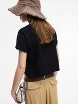 Remera blanca de algodón, corte crop, con cuello redondo y mangas cortas con dobladillo.