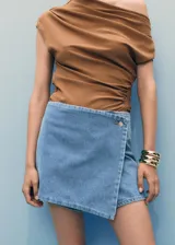 Short pantalón (skort) de denim azul claro, tiro medio, con diseño cruzado en la parte delantera asegurado con un botón y cierre de cremallera en la parte posterior.