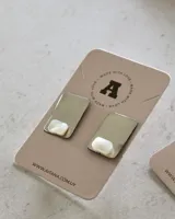 Par de aros rectangulares plateados con incrustación de nácar en una esquina.