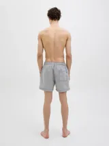 Short de baño celeste y blanco a rayas verticales, confeccionado en tejido seersucker. Cuenta con cintura elástica con cordón ajustable, bolsillos delanteros y un bolsillo trasero.