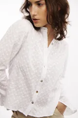 Camisa blanca de broderie de algodón con cuello mao, mangas largas con volados y botones de nácar.