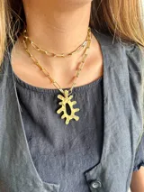 Collar doble dorado con cadena de eslabones rectangulares y dije abstracto.