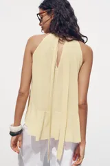 Top color rosa viejo de cuello halter ajustable con lazadas. Detalle de abertura en el delantero y volantes en el mismo tejido.