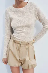 Top de punto color beige con textura, cuello redondo y manga larga.