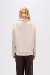 Campera color beige de corte recto, con cuello de piel sintética, cierre frontal con cremallera, bolsillos laterales con cremallera y cordón ajustable en el ruedo.