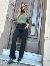 Pantalón negro de corte recto con bota levemente acampanada, de algodón y lycra, con pretina con presillas, elástico y faja.