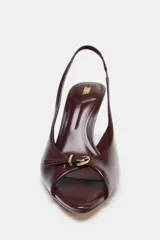Sandalia destalonada color marrón con punta fina, tacón de aguja y tira delantera con detalle de hebilla dorada.