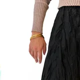 Pulsera dorada de bronce, compuesta por múltiples pulseras finas entrelazadas.