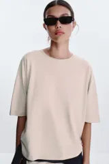 Camiseta color beige de corte amplio, cuello redondo y mangas cortas.